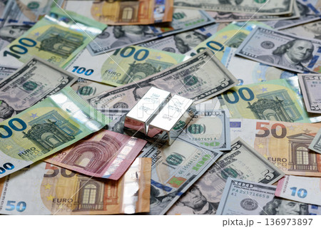 A silver bar, white metal against a backdrop of money, as a concept for the sales. A silver bar A silver bar, white metal against a backdrop of money, as a concept for the sales. A silver bar 136973897