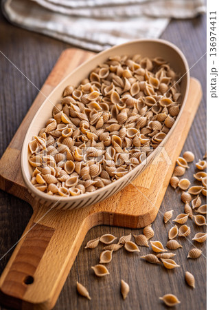 Wholegrain conchiglie pasta in bowl on wooden table. 136974411