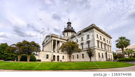 Scenic exterior view of the historic architecture and dome of the South Carolina State House surrounded by trees and grass in Columbia, South Carolina, United States. 136974496