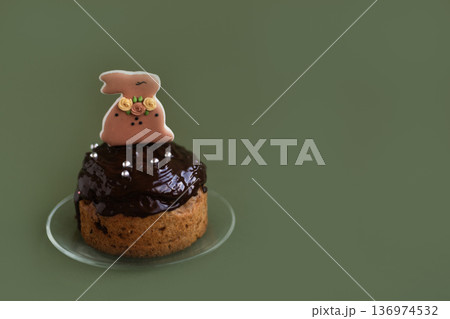 Easter cake topped with chocolate and bunny figurine on green background, bright holiday concept with copy space Easter cake topped with chocolate and bunny figurine on green background, bright holiday concept with copy space 136974532