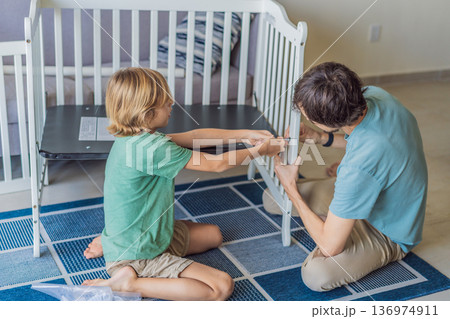 Father and older brother assembling a baby crib at home, preparing for a newborn arrival. Warm family moment full of care and anticipation. Parenthood, sibling bond and home preparation concept Father and older brother assembling a baby crib at home, preparing for a newborn arrival. Warm family moment full of care and anticipation. Parenthood, sibling bond and home preparation concept 136974911