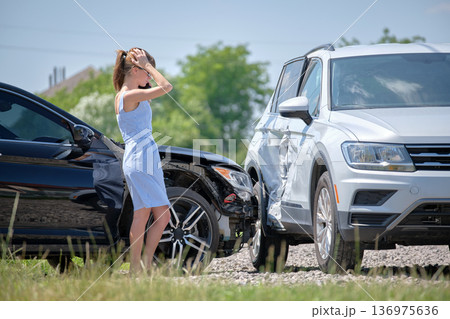 Sad female driver speaking on sellphone on street side calling for emergency service after car accident. Road safety and insurance concept 136975636