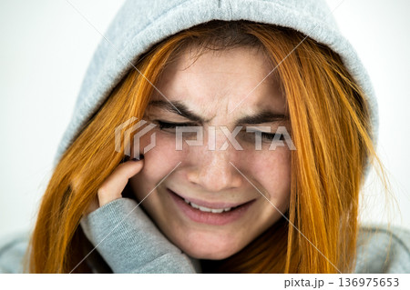 Close up portrait of sad depressed young redhead woman wearing warm hoodie pullover. Close up portrait of sad depressed young redhead woman wearing warm hoodie pullover. 136975653