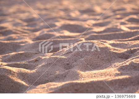 Close up of clean yellow sand surface covering seaside beach illuminated with evening light. Travel and vacations concept Close up of clean yellow sand surface covering seaside beach illuminated with evening light. Travel and vacations concept 136975669