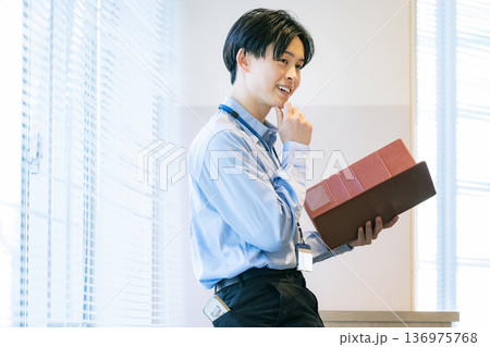 資料を見て考えるビジネスマン 136975768