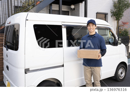 笑顔で荷物を届ける宅配便の男性 笑顔で荷物を届ける宅配便の男性 136976316