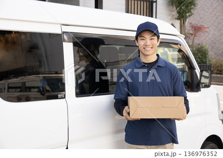 笑顔で荷物を届ける宅配便の男性 136976352