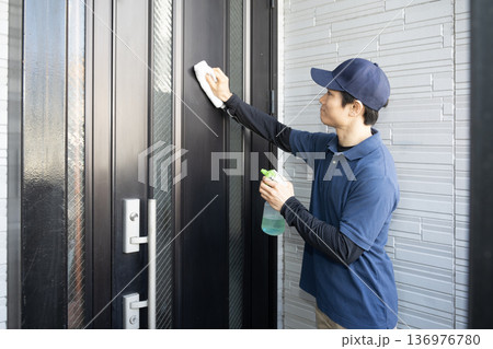 玄関の扉の清掃をするハウスクリーニングの男性 136976780