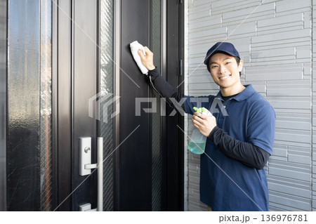 玄関の扉の清掃をするハウスクリーニングの男性 136976781