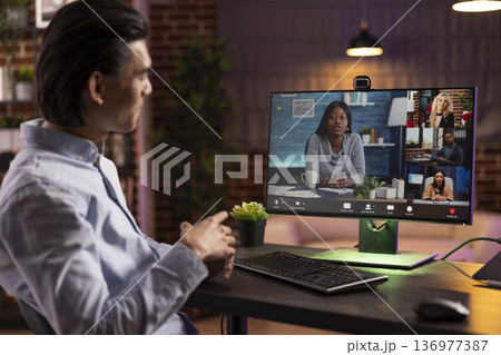 Male entrepreneur joins virtual discussion with multiethnic colleagues to plan marketing projects. Self employed man works from home, sharing business updates with shareholders on video conference. Male entrepreneur joins virtual discussion with multiethnic colleagues to plan marketing projects. Self employed man works from home, sharing business updates with shareholders on video conference. 136977387