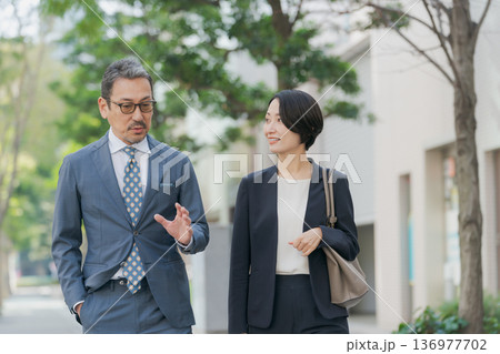 雑談をしながら歩くスーツの男女 136977702
