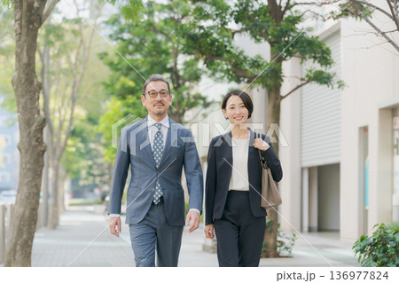 オフィス街を歩くスーツの男女 オフィス街を歩くスーツの男女 136977824