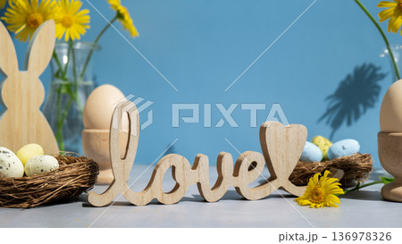 Wooden word LOVE traditional greeting to christian holiday. Festive mood composition with bunnies and yellow flowers on pastel blue background. Sustainable natural materials Wooden word LOVE traditional greeting to christian holiday. Festive mood composition with bunnies and yellow flowers on pastel blue background. Sustainable natural materials 136978326