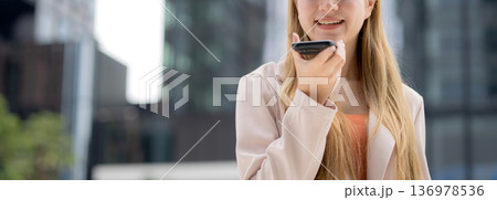 Young caucasian businesswoman using voice message on smartphone with chatbot or AI. 136978536