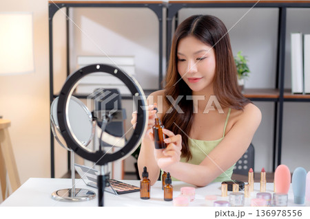 Young asian woman demonstrating serum on hands on social media at home. Young asian woman demonstrating serum on hands on social media at home. 136978556