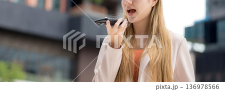 Young caucasian businesswoman using voice message on smartphone with chatbot or AI. 136978566