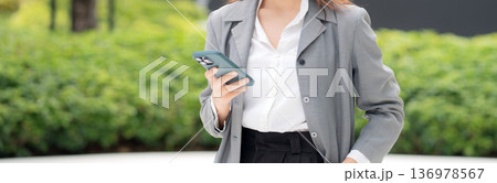 Young asian businesswoman using chatbot or AI message on smartphone outdoors. Young asian businesswoman using chatbot or AI message on smartphone outdoors. 136978567