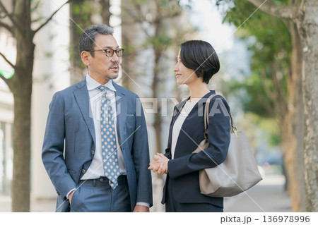 雑談をする歩くスーツの男女 雑談をする歩くスーツの男女 136978996