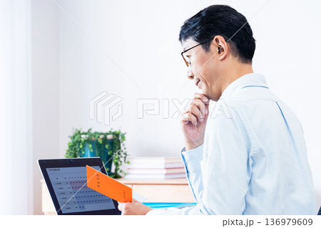 年金手帳を見ながら考える中高年男性 136979609