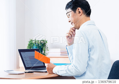 年金手帳を見ながら考える中高年男性 136979610