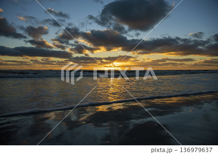 Evening landscape of sea water waves crushing on sandy beach at sunset Evening landscape of sea water waves crushing on sandy beach at sunset 136979637
