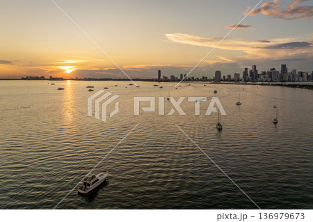 Florida travel destination. Recreational yachts and fishing boats on anchor in Biscayne Bay. Evening urban skyline with high-rises in downtown 136979673
