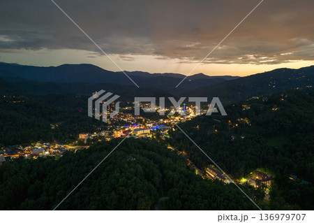 Gatlinburg, Tennessee at night with illuminated Parkway street lined with restaurants, attractions and retail shops for visitors. Forested Appalachian hills surrounding American vacation town. Gatlinburg, Tennessee at night with illuminated Parkway street lined with restaurants, attractions and retail shops for visitors. Forested Appalachian hills surrounding American vacation town. 136979707