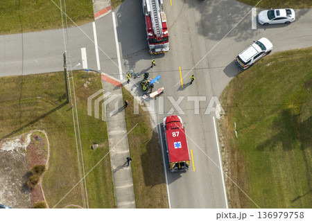 Victim of car accident on medical stretcher. First responders responding to car hit cyclist on street. Emergency medical technicians helping person of vehicle hitting pedestrian on road in USA Victim of car accident on medical stretcher. First responders responding to car hit cyclist on street. Emergency medical technicians helping person of vehicle hitting pedestrian on road in USA 136979758