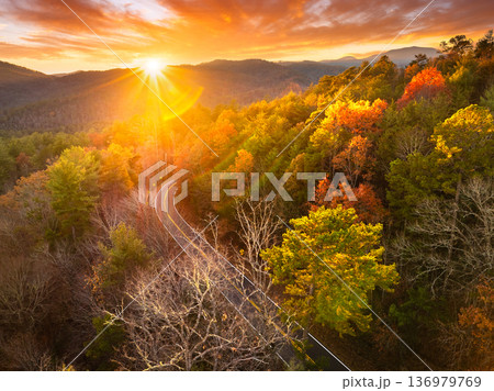 Scenic drive through Tennessee Appalachians at sunset in fall season. Car traveling on curvy forest road under vibrant autumn foliage Scenic drive through Tennessee Appalachians at sunset in fall season. Car traveling on curvy forest road under vibrant autumn foliage 136979769