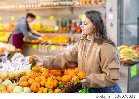 Young woman choosing tangerines in vegetable shop Young woman choosing tangerines in vegetable shop 136979938