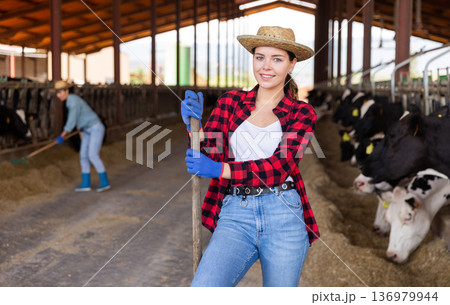 Female farmer in straw hat posing in cowshed Female farmer in straw hat posing in cowshed 136979944