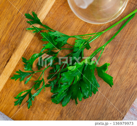 Parsley sprigs on wooden cutting board 136979973