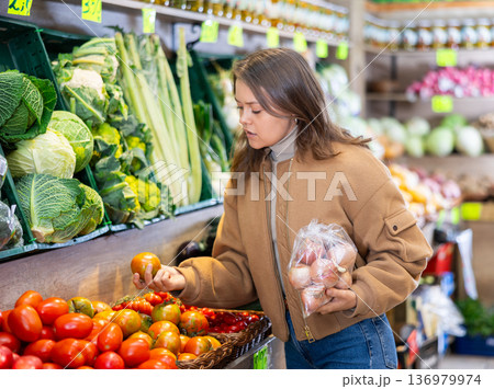 Young girl buying tomatoes in grocery store 136979974