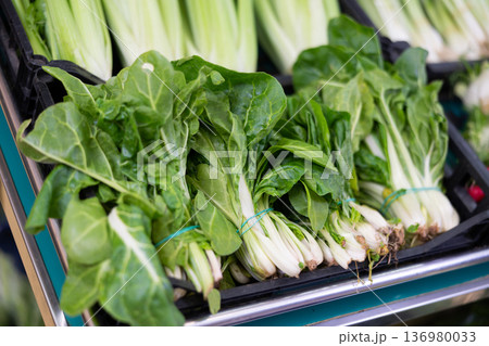 Bunches of fresh spinach lie on counter in shop 136980033