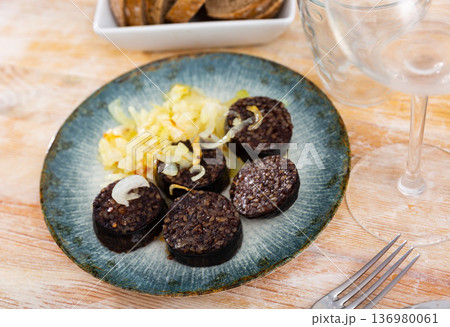 Slices of fried morcilla served with caramelized onions 136980061
