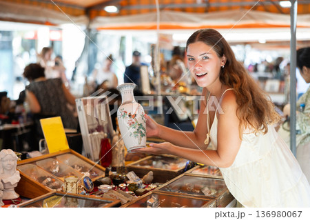 Interested young woman choosing interesting antique things at traditional flea market 136980067