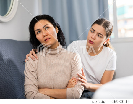 Woman comforting her friend after a domestic quarrel while sitting on couch Woman comforting her friend after a domestic quarrel while sitting on couch 136980139