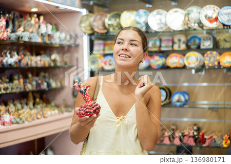 Happy young woman choosing statue of Spanish dancer among various souvenirs in gift shop in Barcelona Happy young woman choosing statue of Spanish dancer among various souvenirs in gift shop in Barcelona 136980171