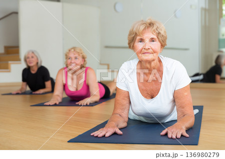 Senior women practicing cobra pose Senior women practicing cobra pose 136980279