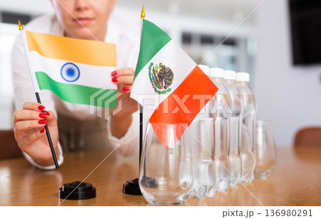 Unrecognizable girl sets midget flags of Mexico and India before international negotiations 136980291