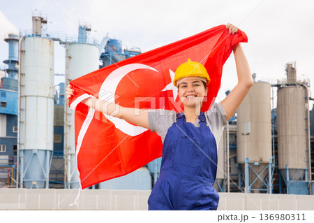 Happy woman waving flag of Turkey against the background of modern factory 136980311