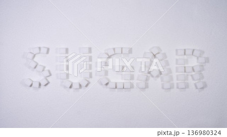 Creative arrangement of sugar cubes forming the word sugar on a white background suitable for educational or culinary themes 136980324
