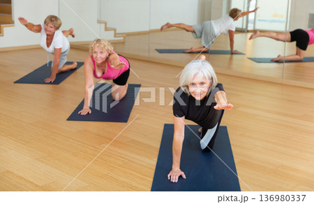 Mature active women perform a stretching exercise 136980337