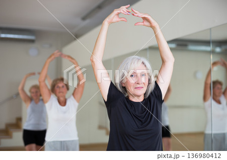 Mature woman learning classical ballet technique in choreography class Mature woman learning classical ballet technique in choreography class 136980412