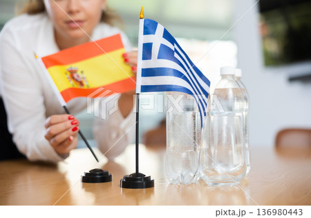 Young female secretary preparing room for international negotiations between greece and spain Young female secretary preparing room for international negotiations between greece and spain 136980443