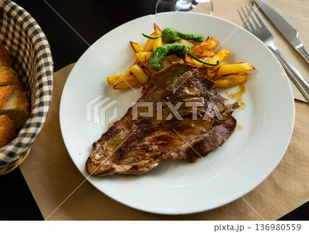 Tasty piece of grilled beef served with potatoes and pepper Tasty piece of grilled beef served with potatoes and pepper 136980559
