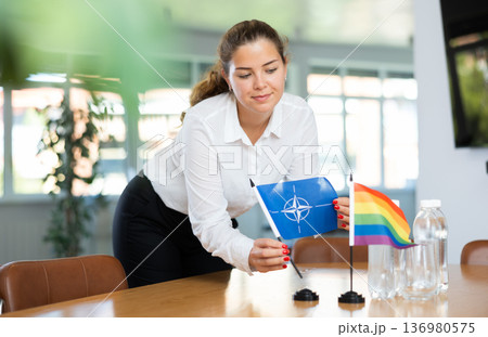 Young lady sets miniatures flags of LGBT and NATO before international negotiations 136980575