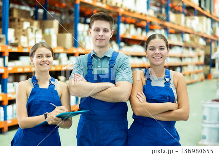 Young female and male employees of store goods for repair and construction are standing in warehouse 136980655