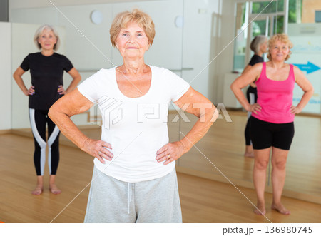 Senior woman stretching between asanas during group yoga training Senior woman stretching between asanas during group yoga training 136980745