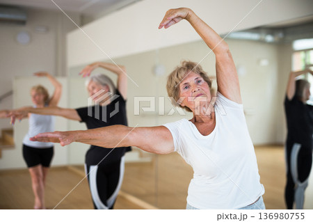 Mature women performing ballet dance in exercise room Mature women performing ballet dance in exercise room 136980755